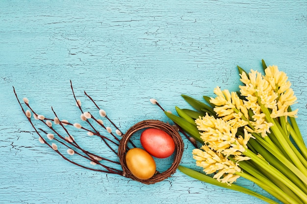 Ovos de páscoa e flores amarelas sobre fundo azul