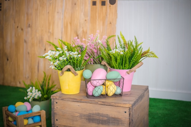 Ovos de Páscoa e flores da primavera na cesta, caixa na mesa de madeira