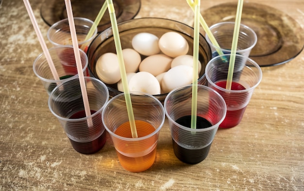 Ovos de Páscoa e tintas líquidas coloridas sobre a mesa para crianças usando tintura e pintura em ovos cozidos brancos durante a preparação para a Páscoa