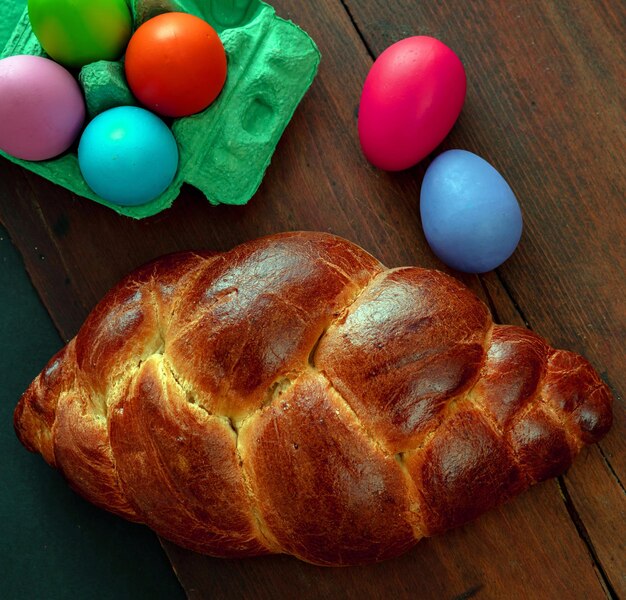 Ovos de Páscoa e tsoureki tricotado pão doce de Páscua grego em fundo de madeira