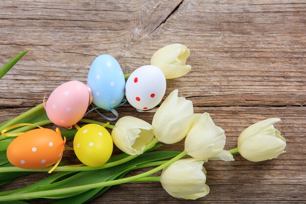 Ovos de Páscoa e tulipas em fundo de madeira e copie o espaço