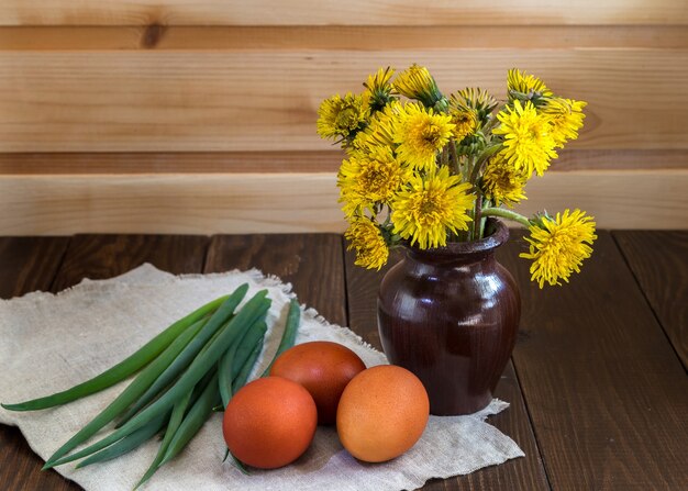 Foto ovos de páscoa e um monte de flores em uma mesa de madeira.