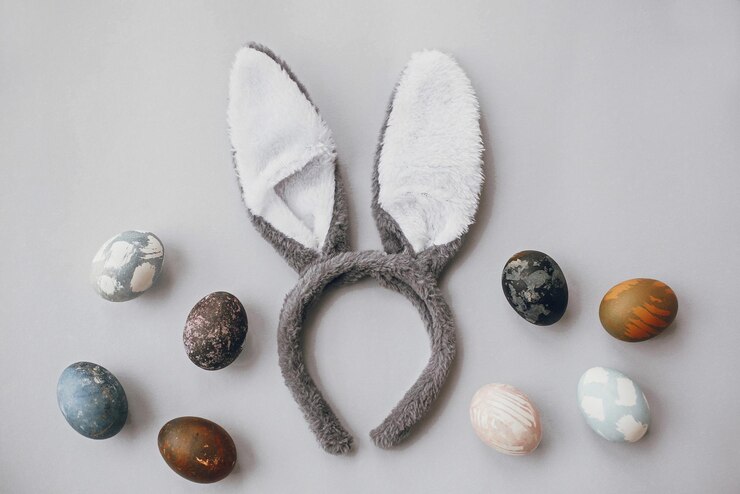 Foto ovos de páscoa elegantes e orelhas de coelho planas sobre papel de parede cinza com espaço para cópia ovos de páscoa coloridos tingidos naturais e orelhas de coelho cinza saudações das estações
