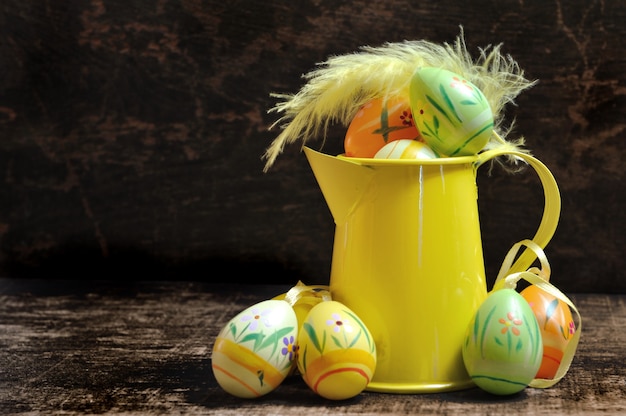 Ovos de Páscoa em um pequeno regador em fundo escuro de madeira