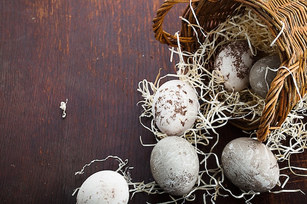 Ovos de Páscoa em uma cesta caramelada na velha mesa marrom