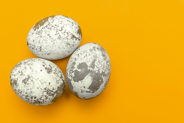 Ovos de páscoa multicoloridos e close up de penas em um prato em um cartão de felicitações de fundo amarelo