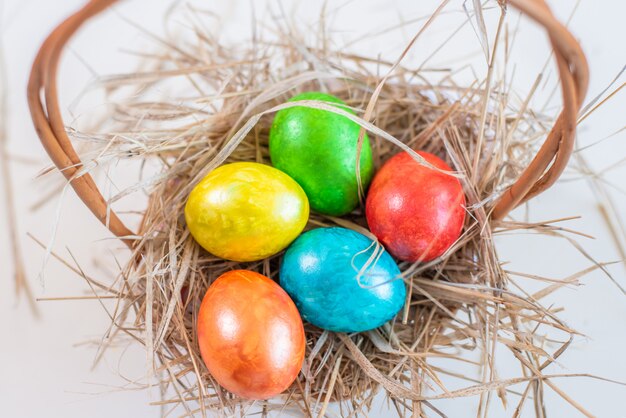 Ovos de Páscoa multicoloridos mentem em um canudo em forma de ninho em uma cesta