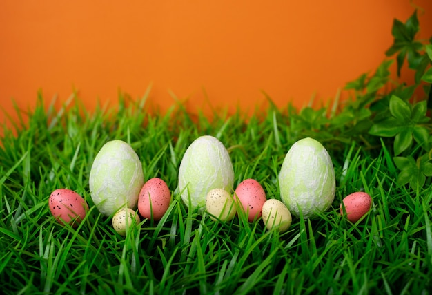 Ovos de Páscoa na grama do prado com parede laranja