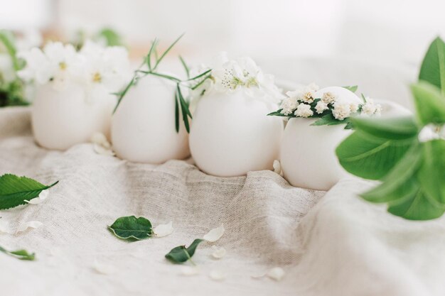 Ovos de páscoa naturais em coroas florais em tecido de linho com ramo de primavera florescente e pétalas brancas