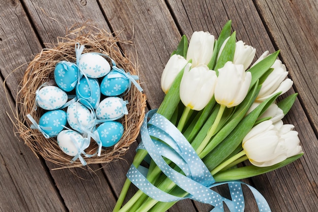 Ovos de Páscoa no ninho e tulipas brancas