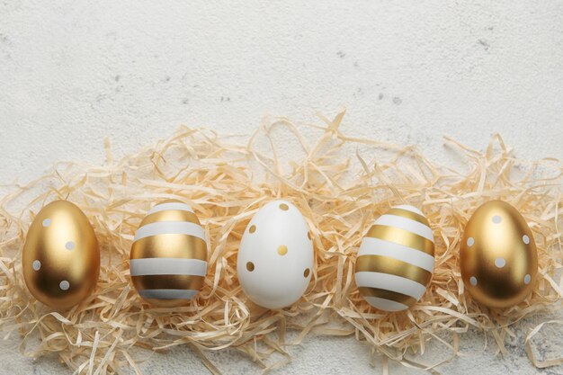 Ovos de Páscoa pintados com tinta dourada sobre fundo de palha