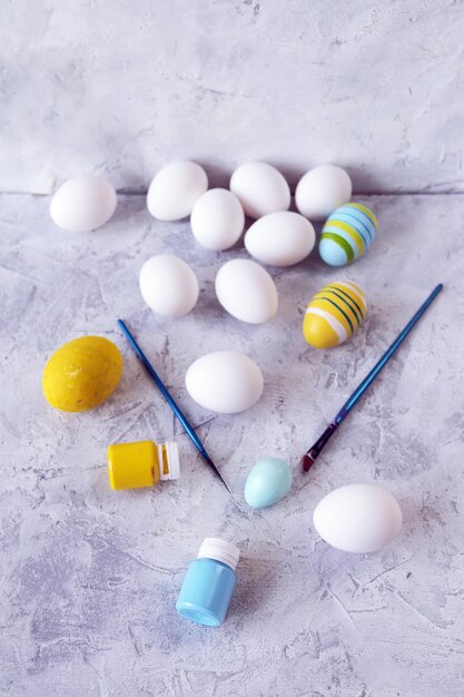 Ovos de Páscoa pintados em cores pastel pincéis amarelos e azuis em uma mesa de concreto