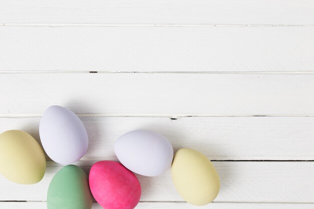 Ovos de Páscoa pintados em cores pastel sobre fundo branco de madeira