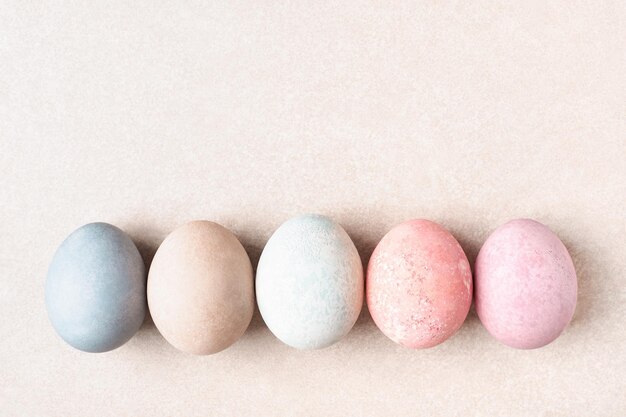 Foto ovos de páscoa tingidos em pastel em linha no espaço de cópia de fundo bege