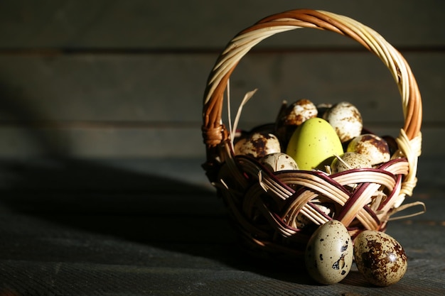 Ovos de pássaros na cesta de vime com fundo de madeira