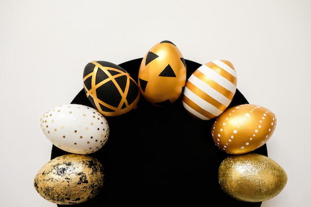 Ovos decorados à moda dourados da Páscoa na placa preta