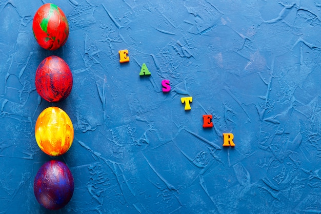 Ovos decorativos coloridos e letras sobre um fundo azul