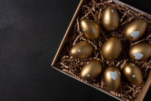 Ovos dourados em caixa de papel em uma mesa Vista superior