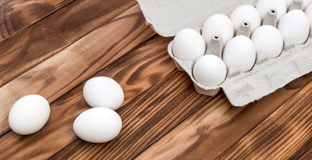 Ovos e recipiente de papelão com ovos em cima da mesa