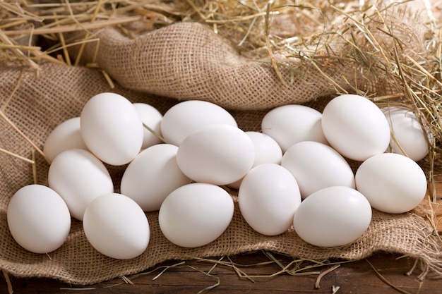 Ovos em uma pilha de feno na mesa de madeira