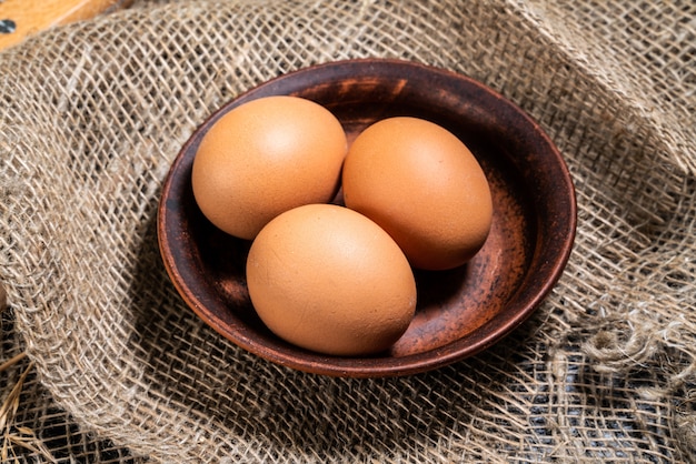 Ovos em uma tigela de barro em um tecido natural. o conceito de fazer pão, assar em casa