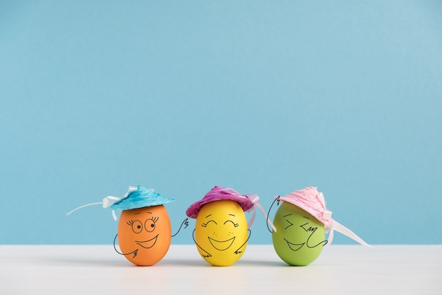 Foto ovos felizes em chapéus rindo. conceito de férias da páscoa com ovos bonitos com caretas. emoções e sentimentos diferentes.