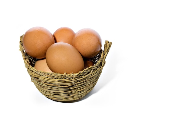 Ovos frescos dentro de uma cesta de vime em fundo branco. Copie o espaço.