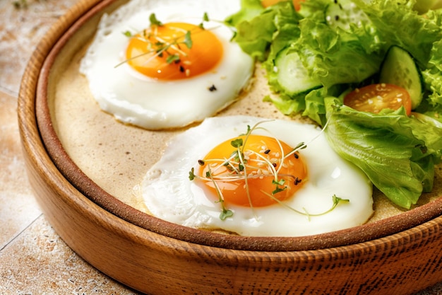 Foto ovos fritos com alface e tomate em fundo bege em luz ensolarada café da manhã saudável