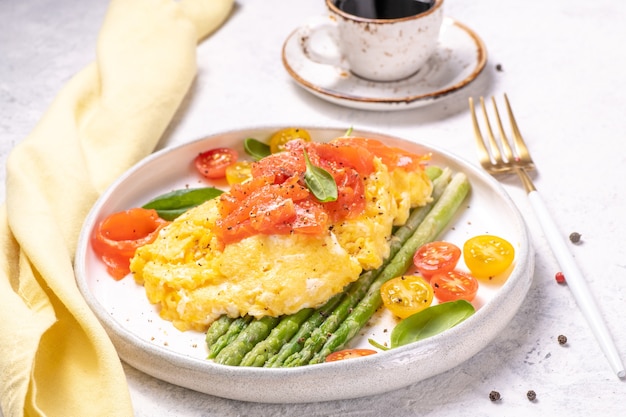 Ovos fritos com espargos verdes e salmão, tomate cereja e espinafre fresco.