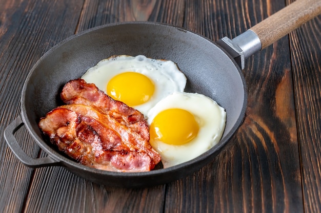 Ovos fritos com fatias de bacon na frigideira