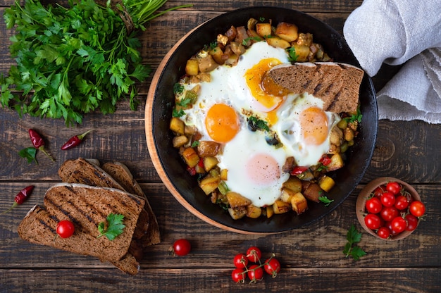 Ovos fritos com shakshuka de vegetais em uma frigideira e pão de centeio