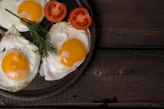 Foto ovos fritos em uma panela com vegetais e ervas em um fundo preto