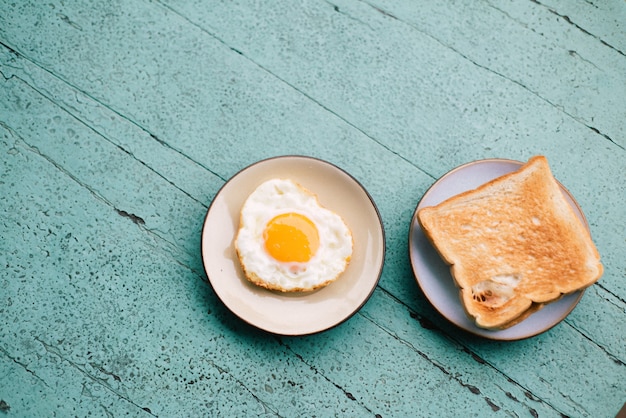 Ovos fritos, torradas, café, café da manhã colocado em uma mesa de madeira azul