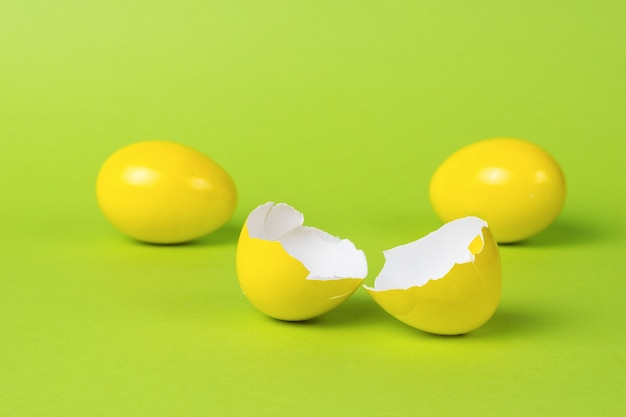 Ovos inteiros e quebrados amarelos brilhantes sobre um fundo verde.