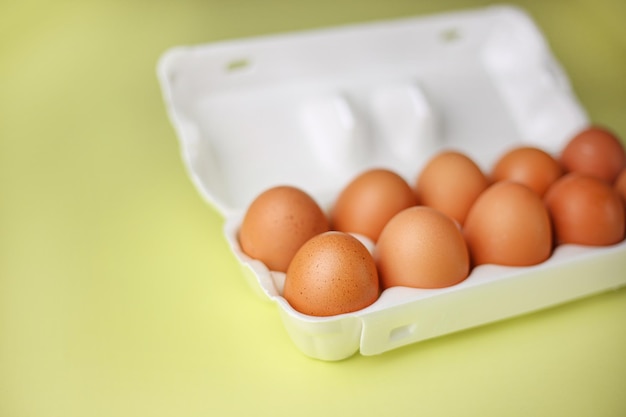 Ovos marrons em embalagens de poliestireno expandido em um fundo amarelo claro isolado