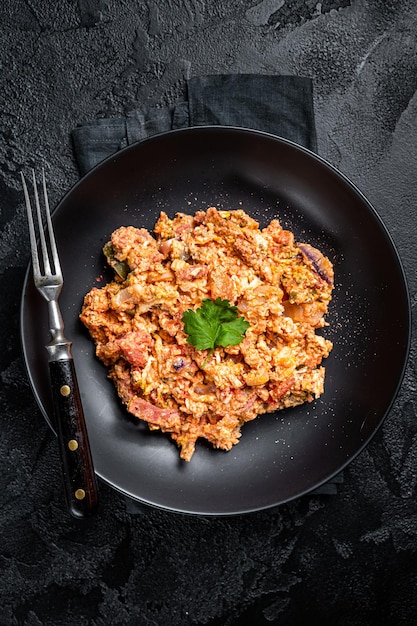 Ovos menemen turcos com tomate, pimentão verde e cebola verde fundo preto vista superior