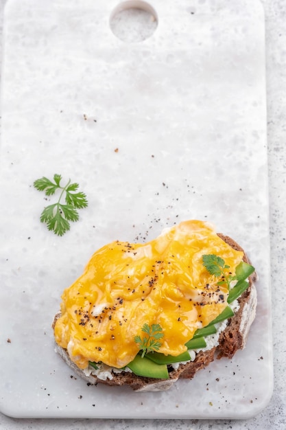 Ovos mexidos com abacate e cream cheese na torrada Comida de café da manhã