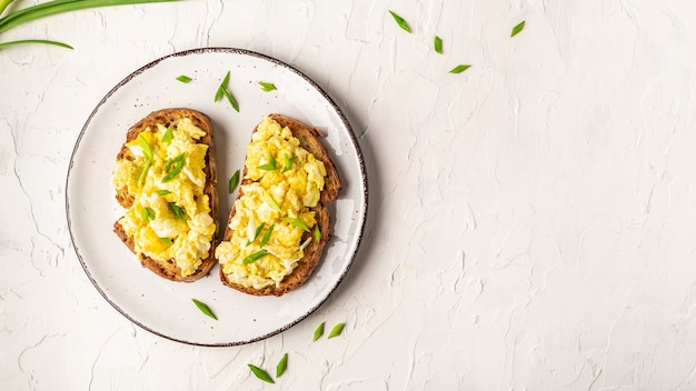 Ovos mexidos com cebola verde em pão crocante integral de centeio de trigo, caseiro, café da manhã saudável ou brunch