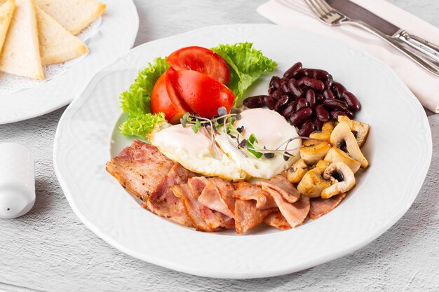 Ovos mexidos com legumes, presunto, tomate, feijão vermelho e torradas de fermento isolado na mesa de mármore branca. Comida caseira. Saboroso café da manhã. Foco seletivo.