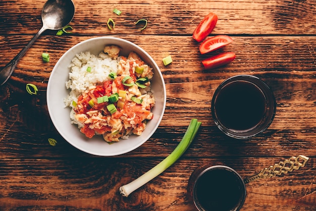 Ovos mexidos com tomate, alho-poró e arroz branco. Café turco e ingredientes fatiados.