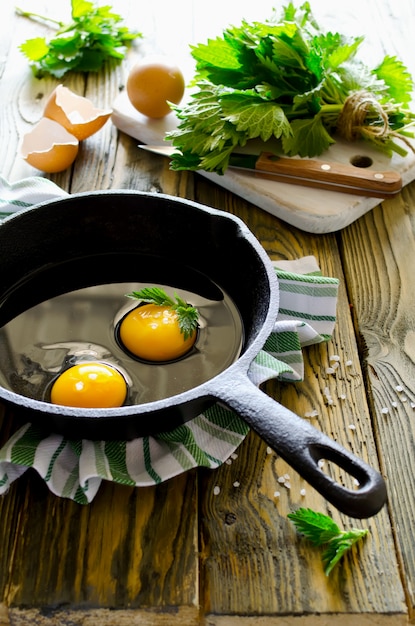 Ovos mexidos com urtigas na panela na mesa de madeira