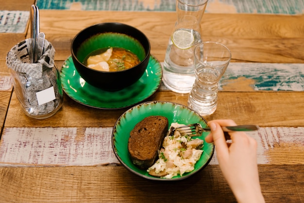 Ovos mexidos em uma tigela de água, ao lado da sopa, menu de almoço em uma mesa de madeira, foco seletivo