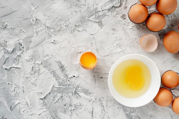 Ovos na mesa com rachado em um meio, gema e proteína no ovo aberto, ovos mexidos cookings