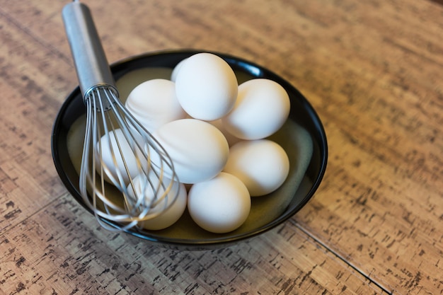 Ovos orgânicos brancos frescos com batedor para omelete