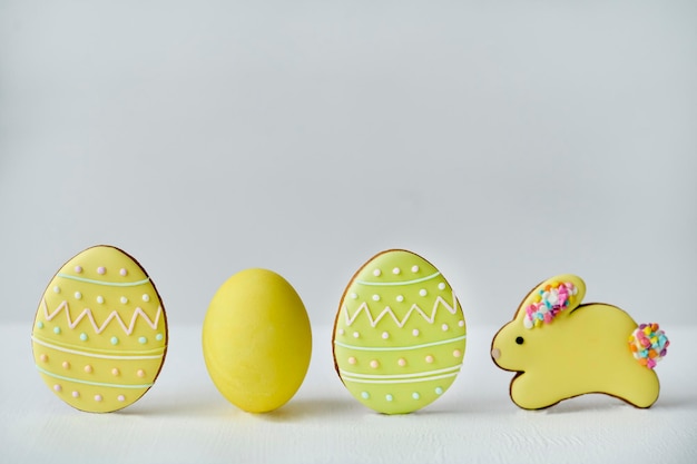 Foto ovos pintados de amarelo e biscoitos amarelos em forma de coelho e ovos em fundo branco