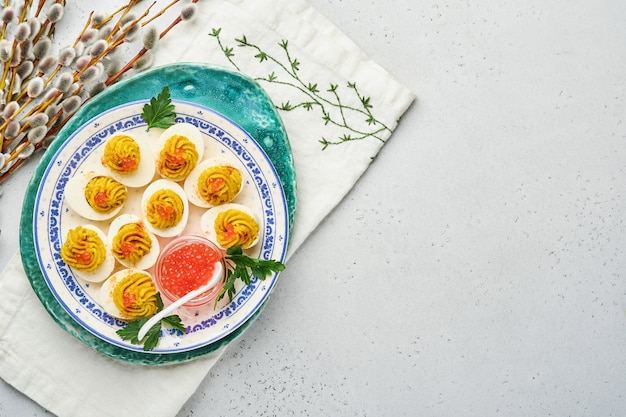 Ovos recheados com caviar vermelho e páprica no prato para aperitivo de mesa de páscoa