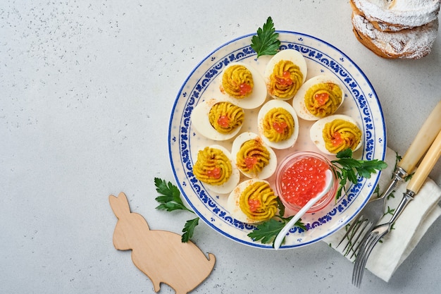 Ovos recheados com caviar vermelho e páprica no prato para mesa de Páscoa de aperitivo, vista de cima, copie o espaço. Prato tradicional para o feriado de Páscoa feliz.