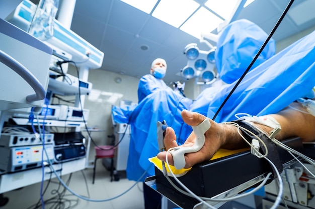 Foto oxímetro de pulso no dedo do paciente durante a operação de cirurgia paciente do sexo masculino deitado na cama de hospital medicina cirurgia ressuscitação conceito de emergência clínica moderna close-up