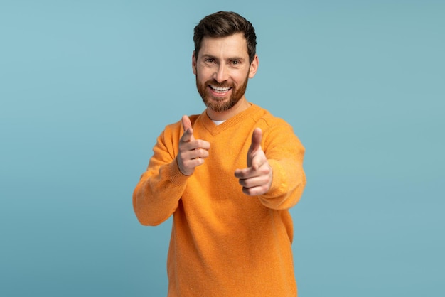 Foto oye tú retrato de un hombre barbudo feliz señalando con los dedos a la cámara contra un fondo azul claro foto de estudio