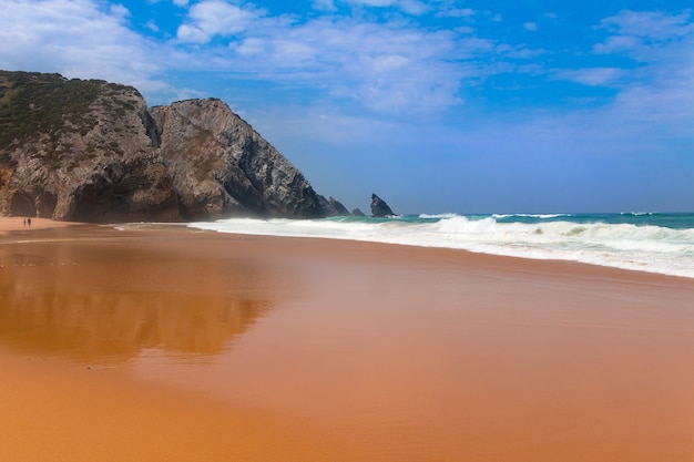 Ozean Sandstrand. Die Felsen im Hintergrund. Surfwelle